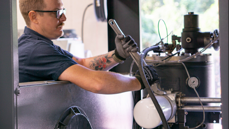 air compressor service technician changing an oil filter